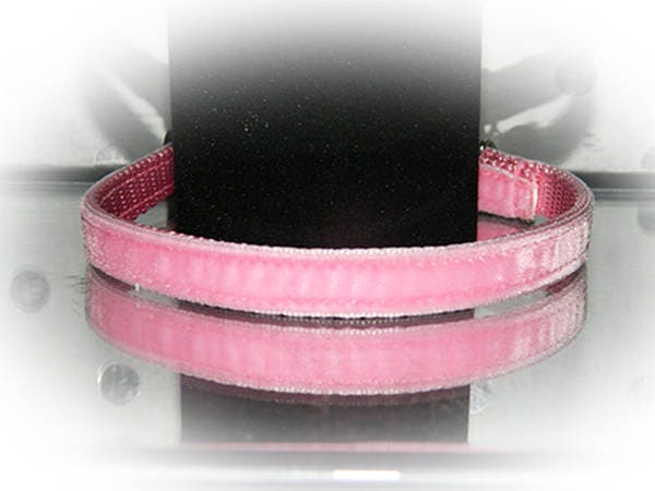 Pink cat collar on a black mannequin with a reflective pattern against a white background