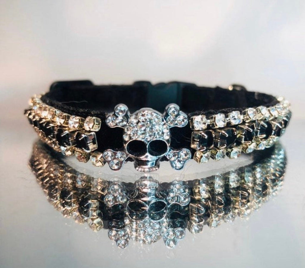Black velvet collar with silver skull design and rows of rhinestones on a reflective surface.