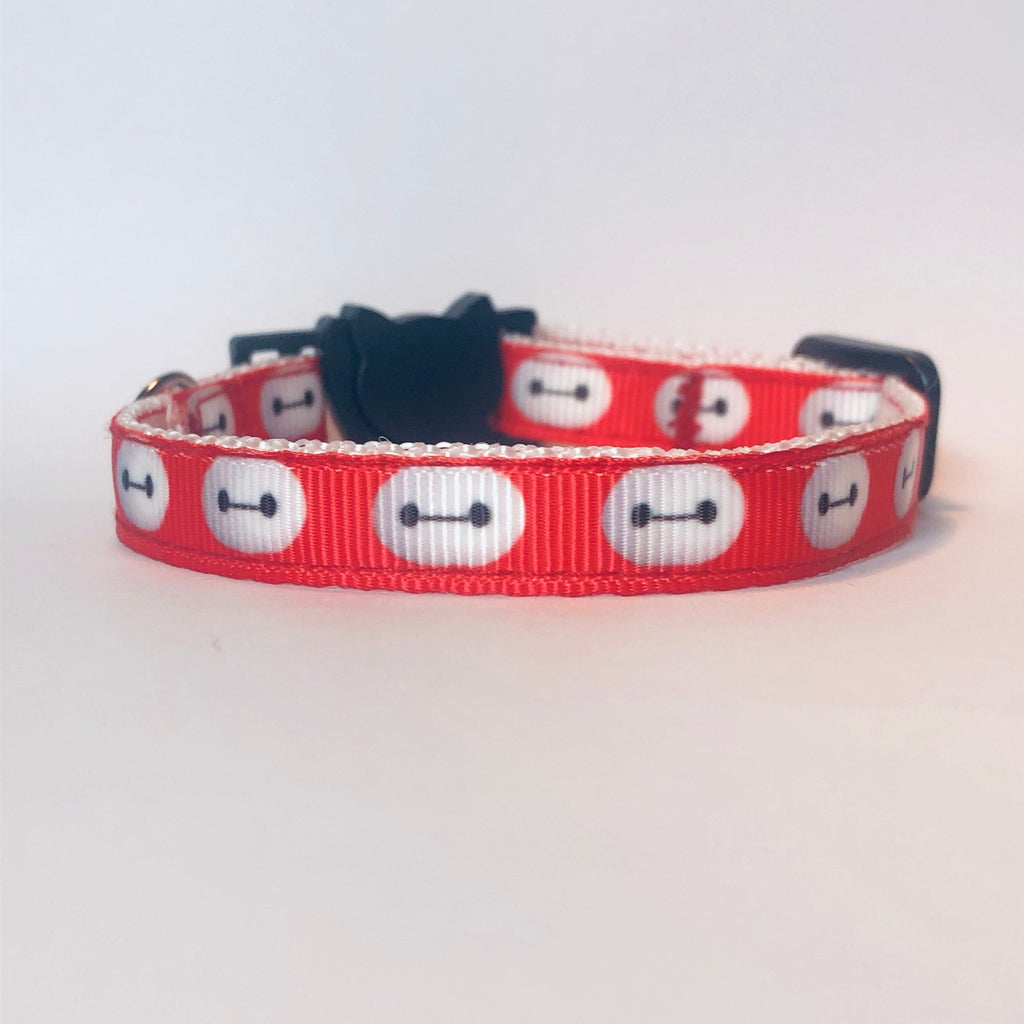 Red cat collar with white face design on a light gray background