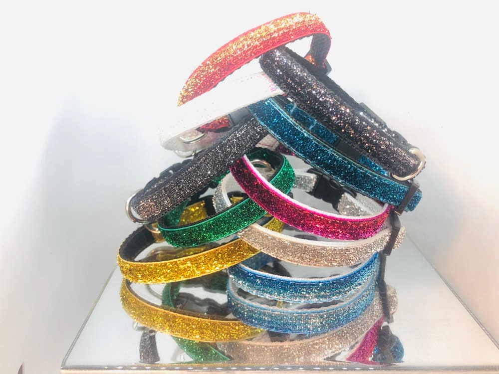 Stack of colorful glittery cat collars in varying colors on a white background