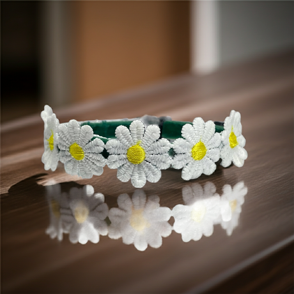 Floral cat collar with white flowers and yellow centers on a reflective surface