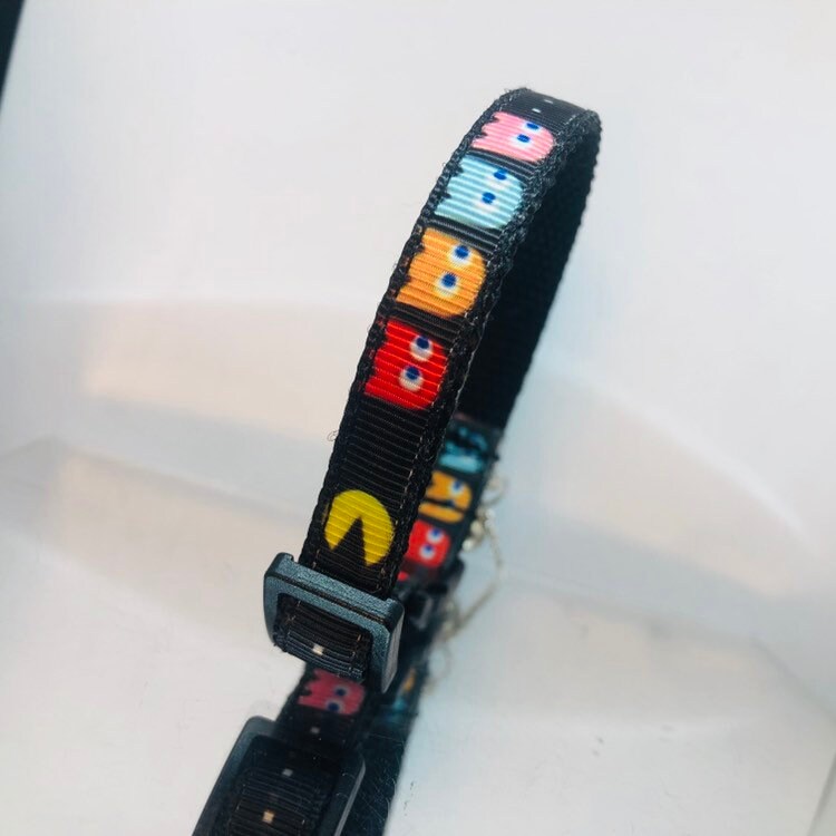 Black collar with colorful cartoon face patterns on a white background