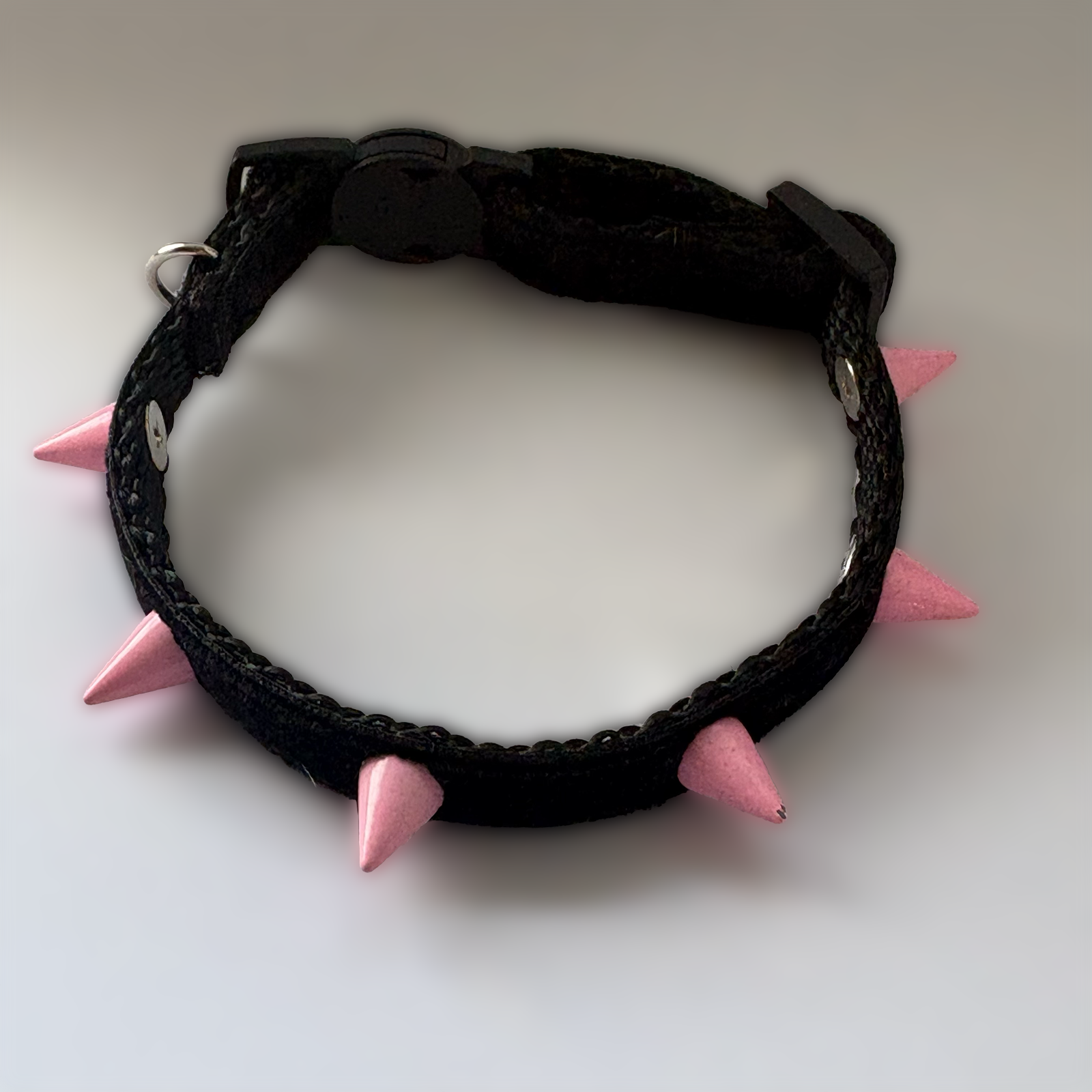 Black velvet collar with pink spikes on a white background