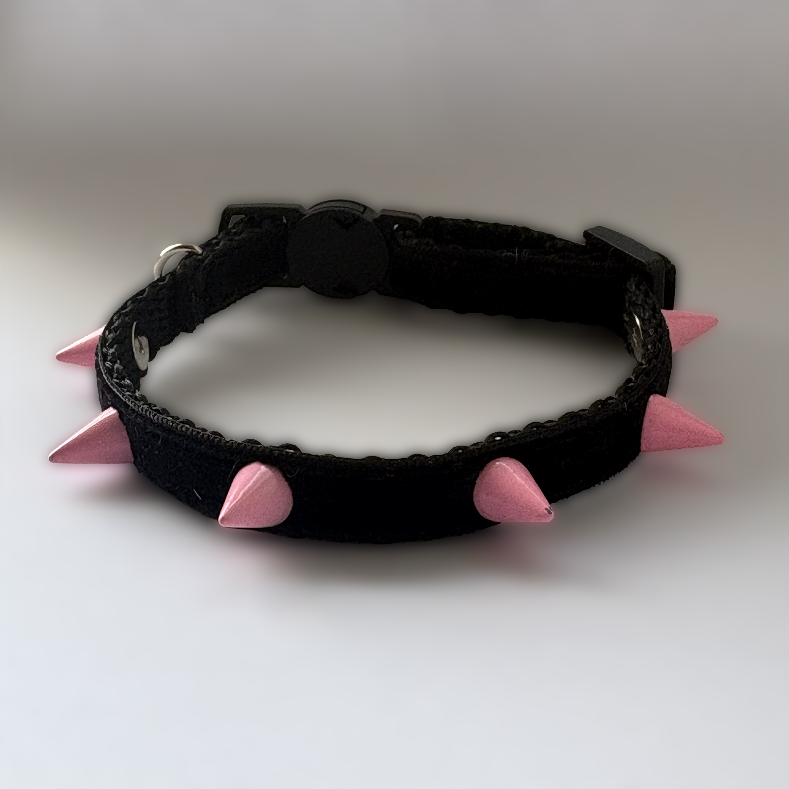 Black cat collar with pink spikes on a white background