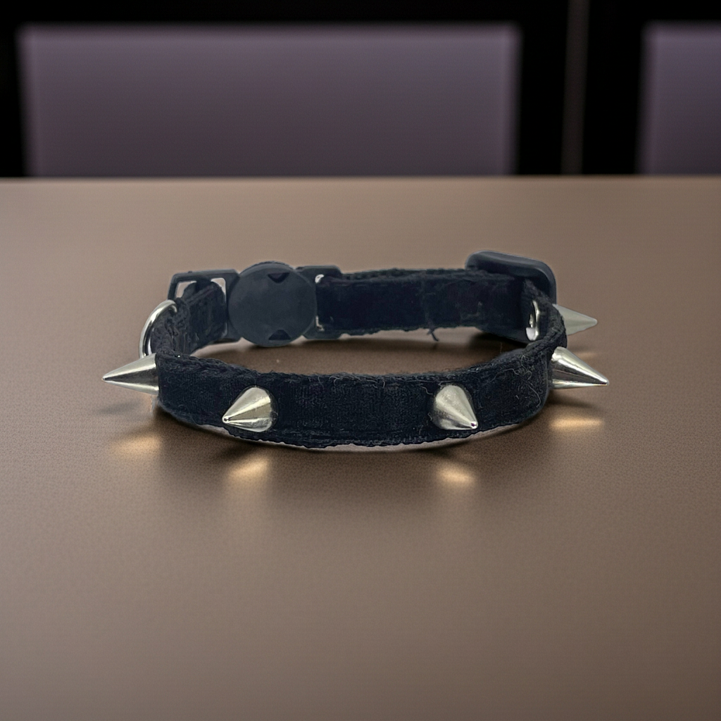 Black velvet collar with silver spikes on a brown surface